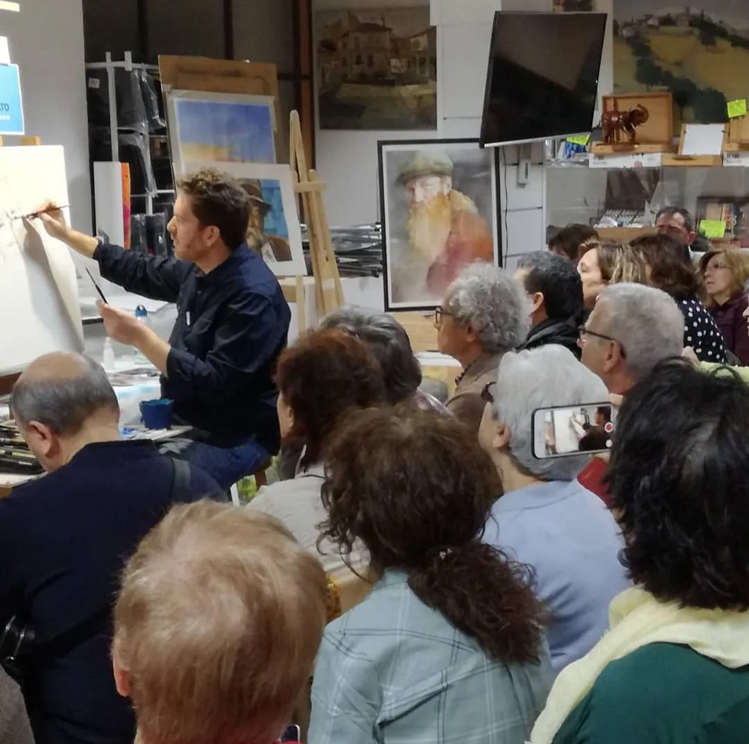 Emmanuel pintando en el caballete ante los alumnos