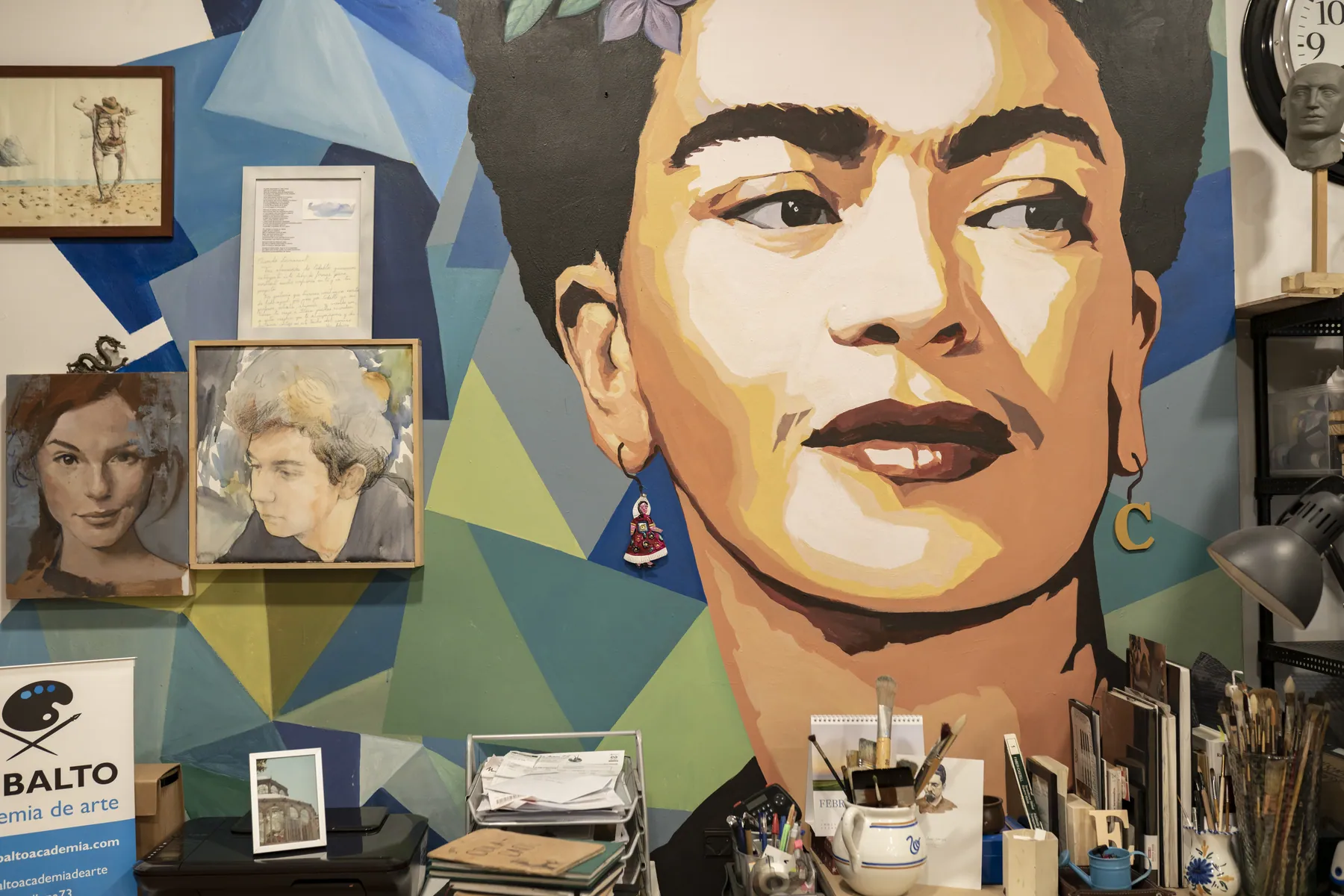 Mural de Frida Kahlo en el estudio junto a estanterías de materiales